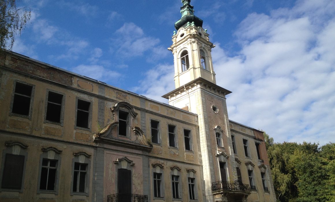 A Small palace with peeling paint against a blue sky with clouds