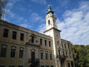 A Small palace with peeling paint against a blue sky with clouds